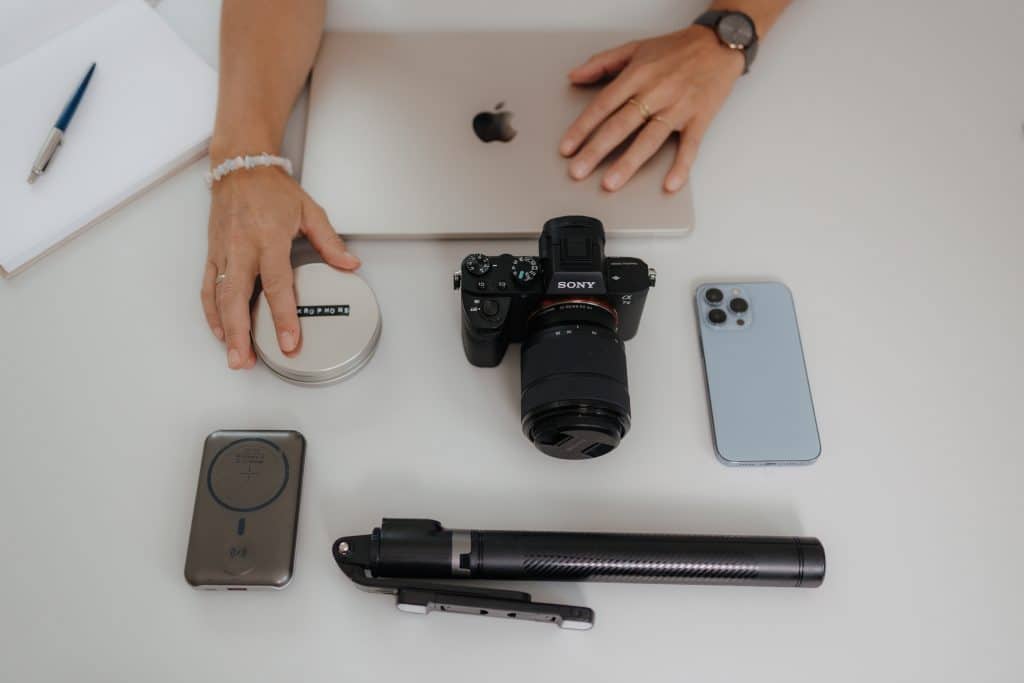Laptop, Handy, Kamera, Stativ liegen auf einem Schreibtisch